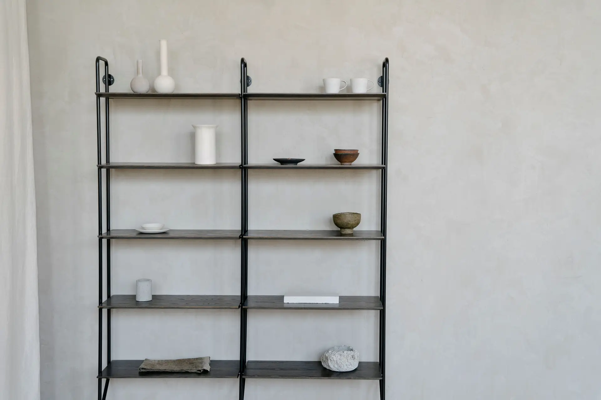 Minimalistinen avohyllykkö kivikeramiikalla ja kirjoilla